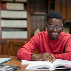 Happy university student reading in library