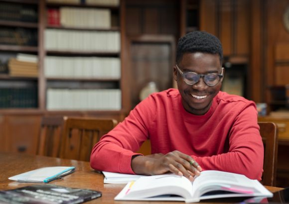 Happy university student reading in library